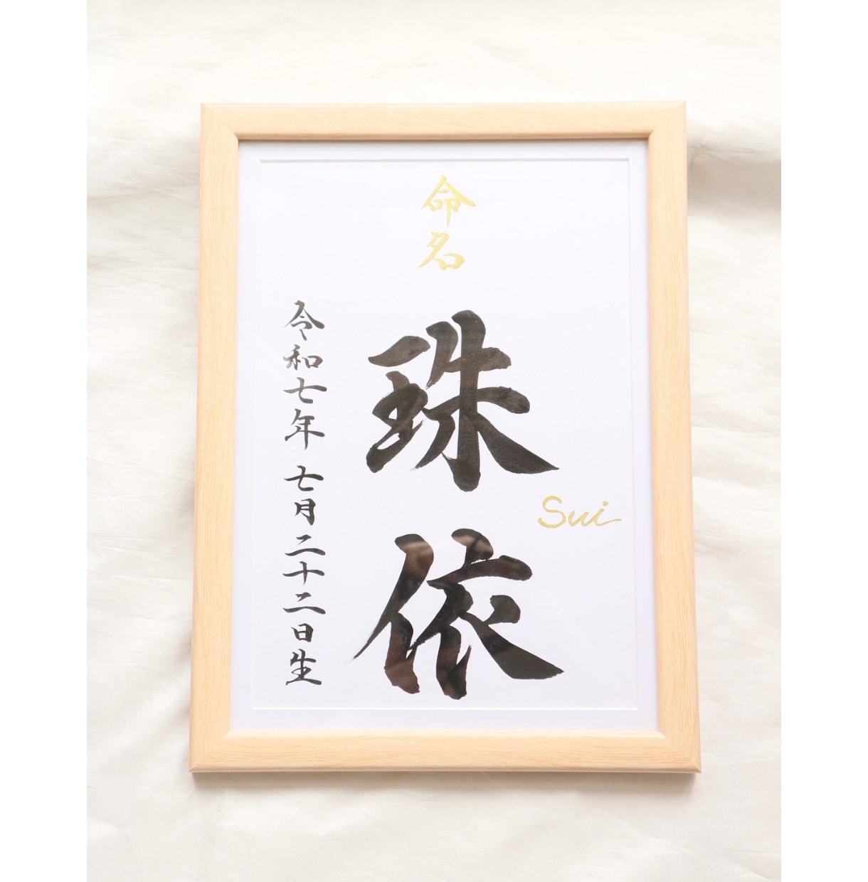 木製の額に入った命名書。金色の「命名」の文字と名前が縦書きで書かれている